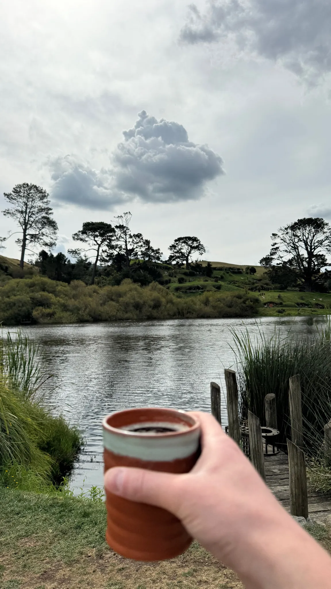 A mug of Oatbarton Brew overlooking the water at Hobbiton.