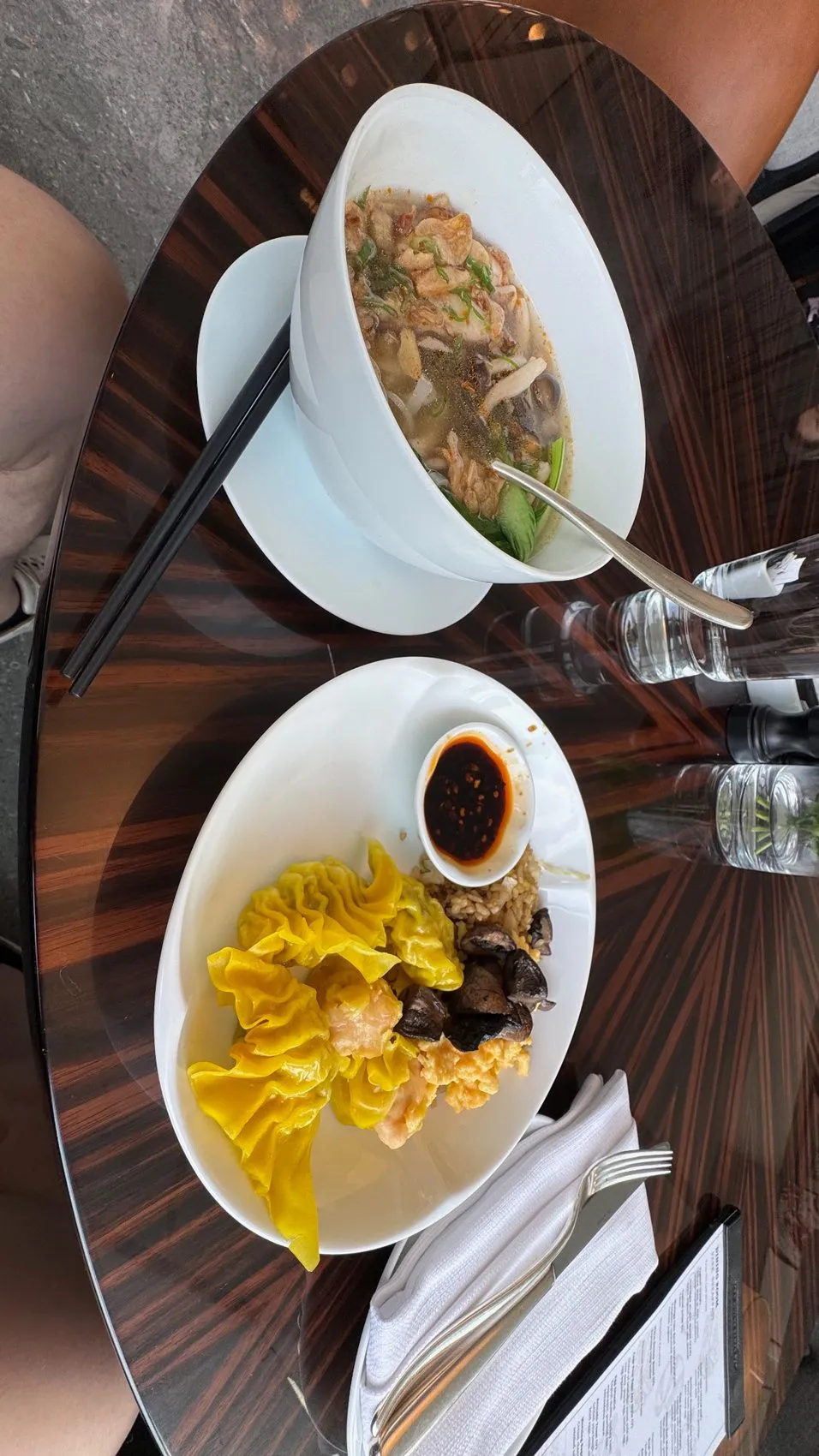 A breakfast plate featuring dim sum, noodles, mushrooms, and a comforting bowl of soup.