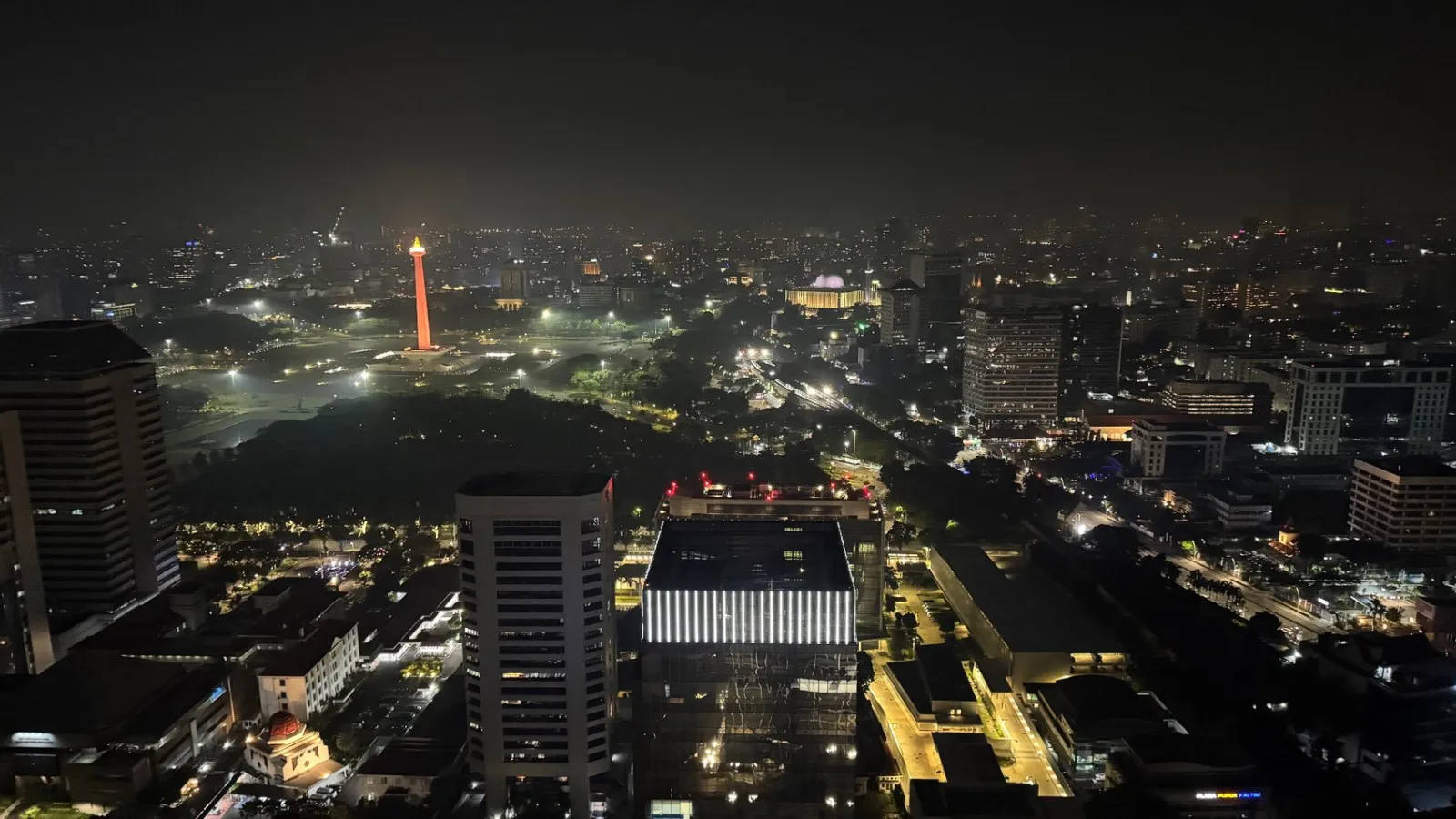 Jakarta after dark, with the illuminated National Monument (Monas) standing out against the skyline.